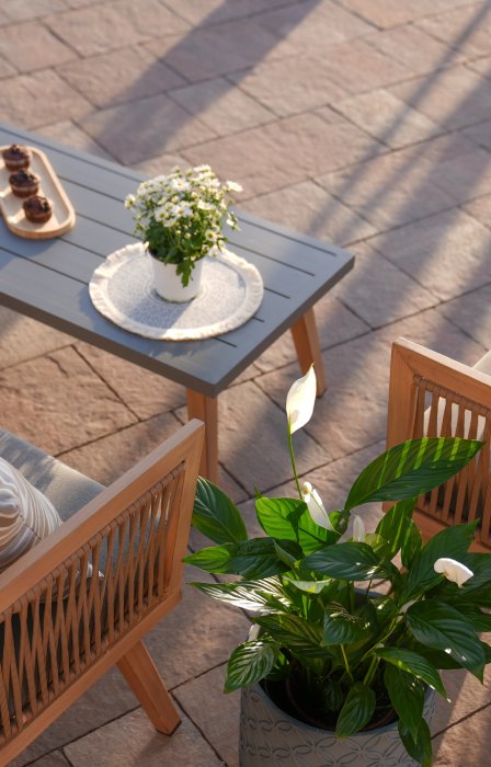 An overhead view of an outdoor patio space with garden tiles, a grey coffee table, and wooden chairs and loveseat.