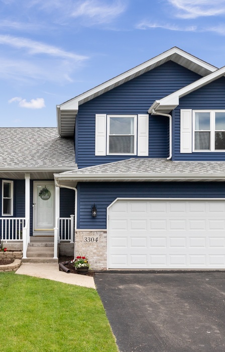 The exterior of a home with blue siding and gray roofs. All of the windows and doors are a bright white.