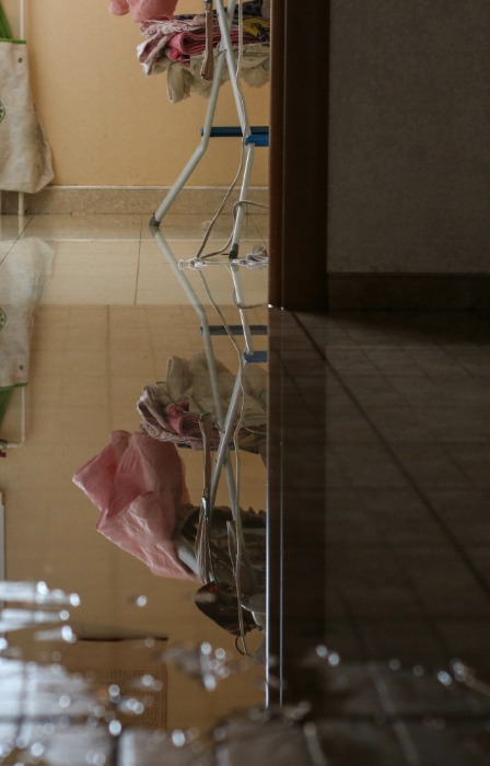 A tile floor covered by a large puddle of water. The puddle extends all the way into the next room.