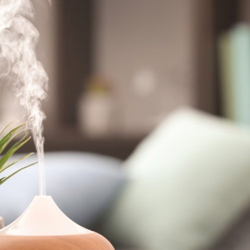 A close-up of an essential oil diffuser emitting steam next to a small desk planter on a wooden table.