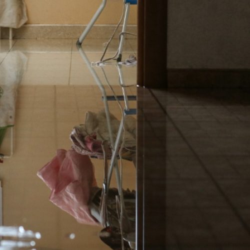 A tile floor covered by a large puddle of water. The puddle extends all the way into the next room.