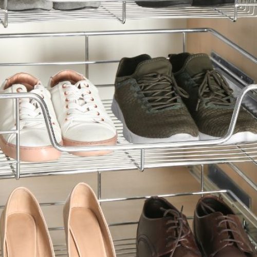 Six pairs of neutral-colored shoes, including flats, heels, and sneakers, are stored in three metal sliding wardrobe drawers.